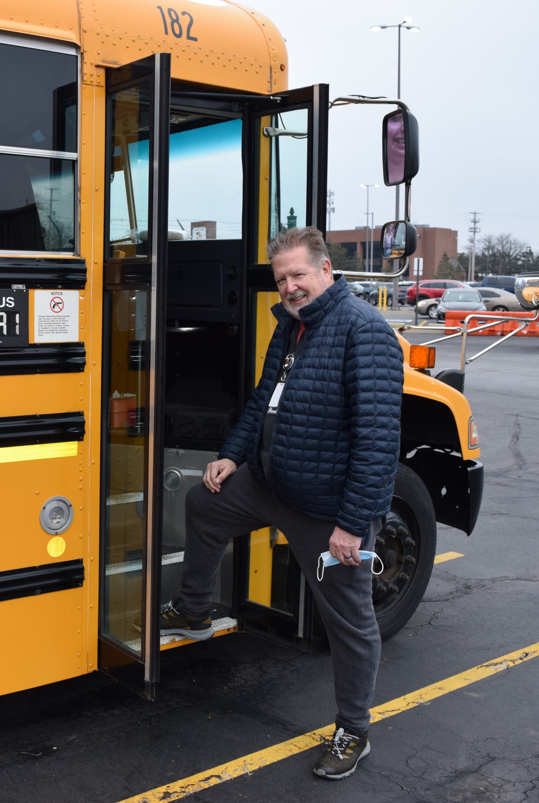 Driver standing on step of school bus.