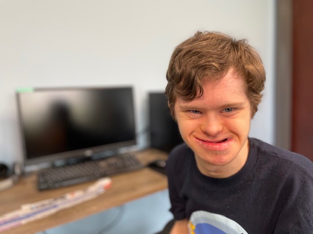 Ryan is smiling and sitting in front of a computer.