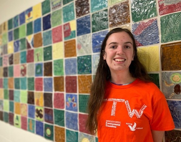 young woman standing in front of colorful wall tiles