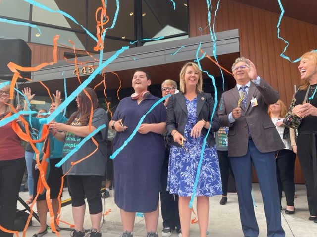 Many people gathered outside the new health center. Colorful ribbons float in the air.