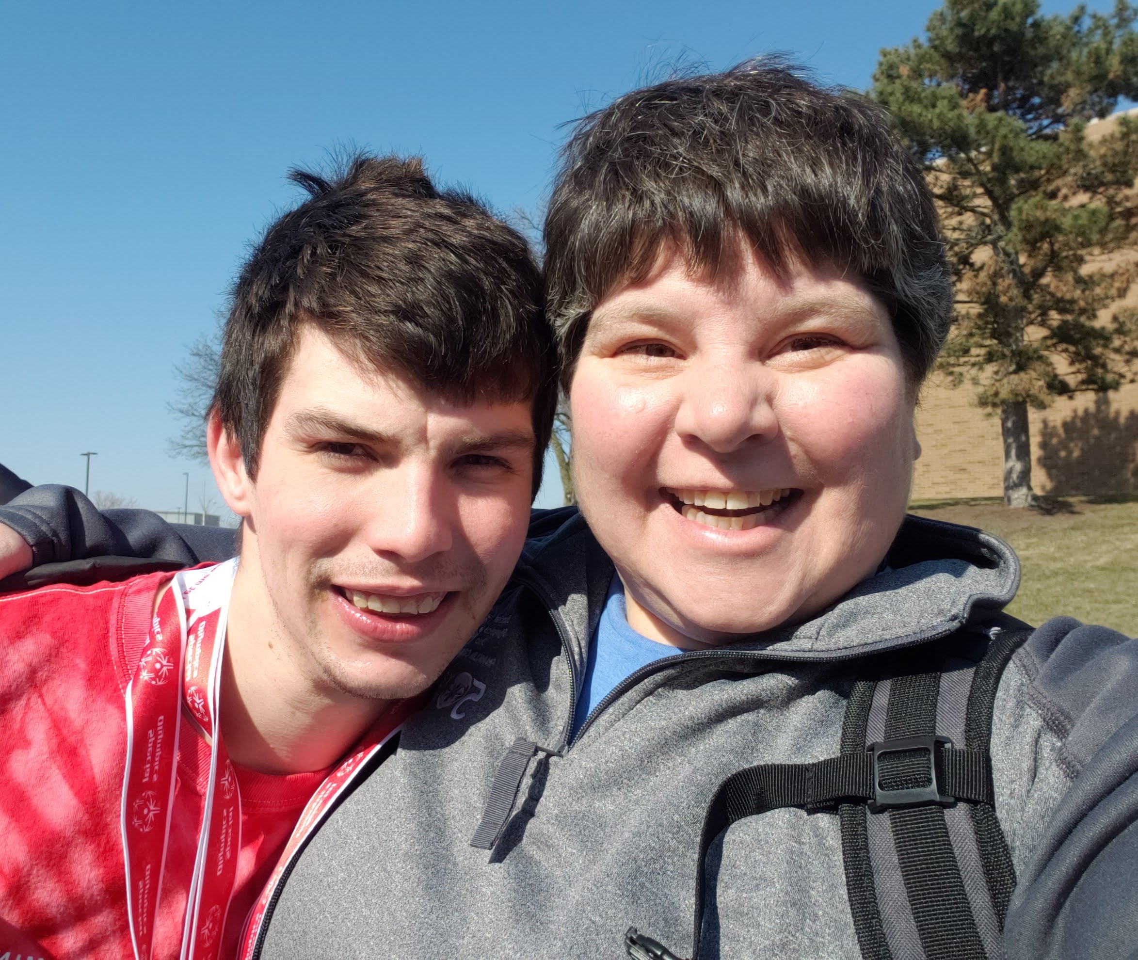 Young man and a woman leaning close together, both of them smiling.