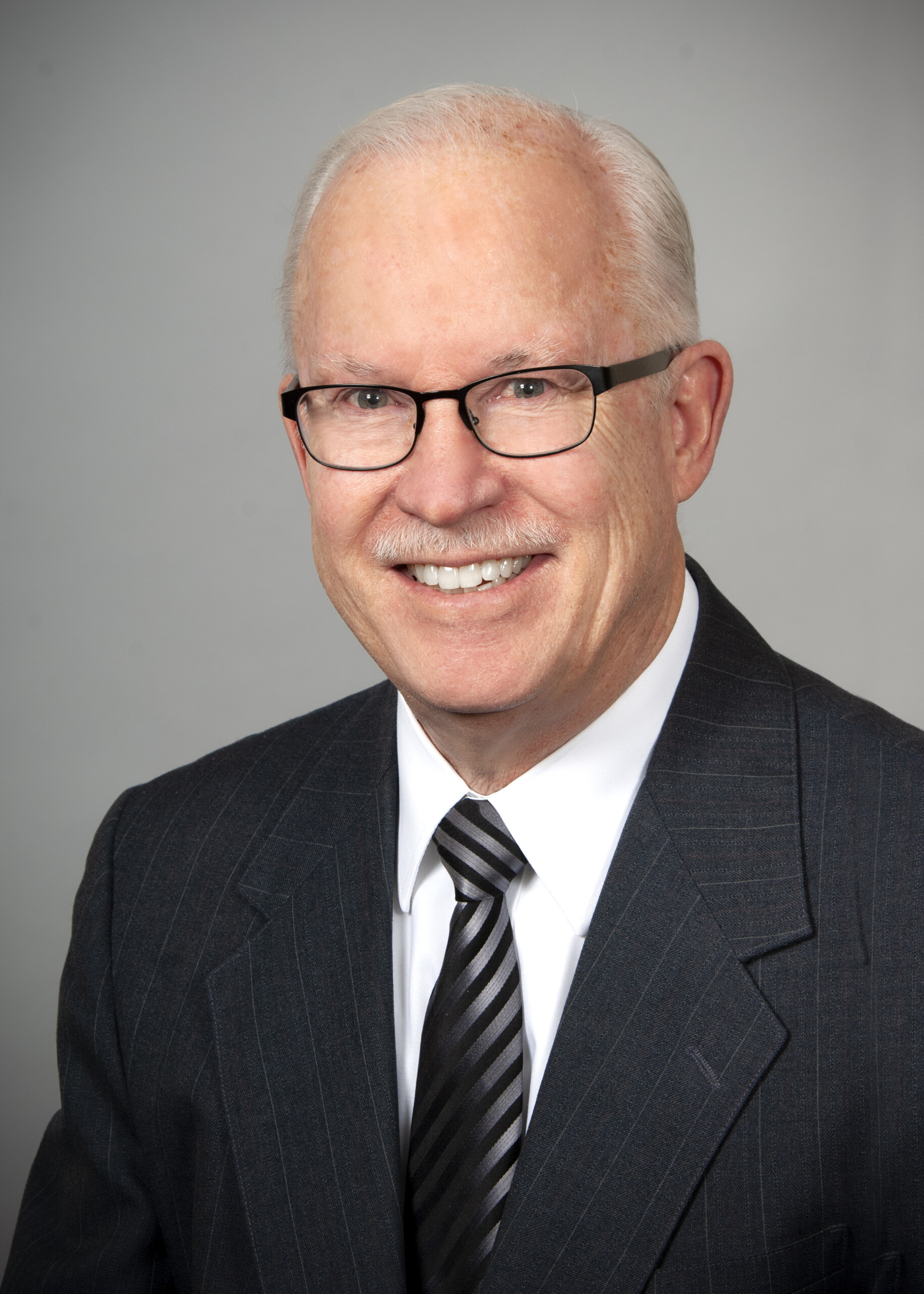 Picture of Jed Morison, wearing glasses and a dark suit